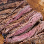 steak sliced onto a wooden cutting board.