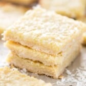 Close up shot of three gooey coconut pie bars stacked on eachother