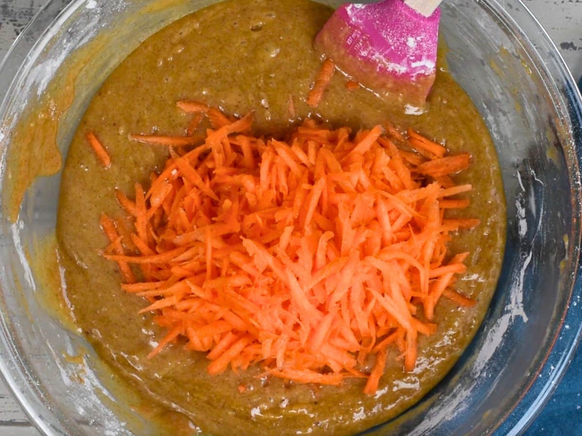 carrot cake batter in bowl with shredded carrots.