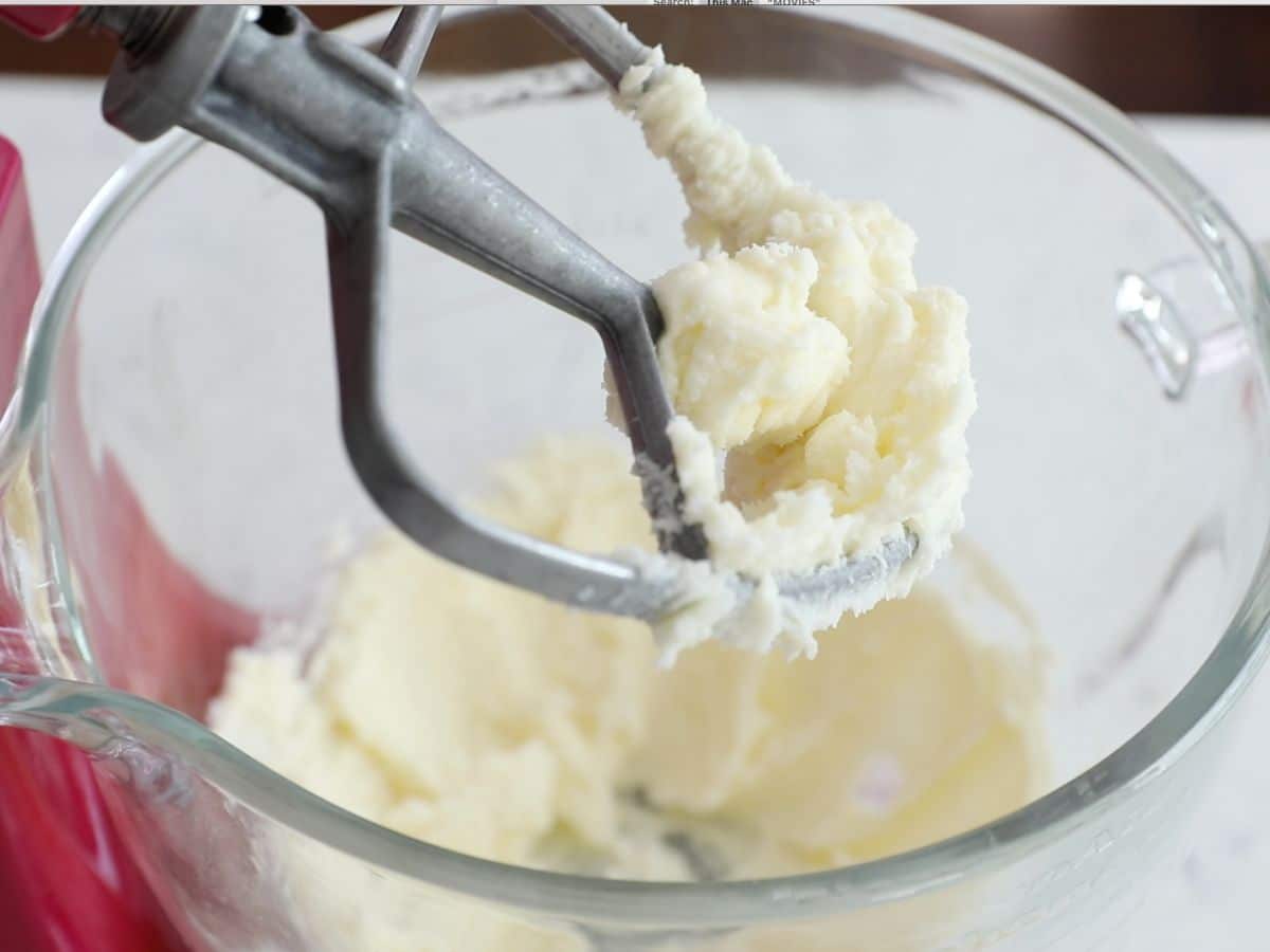 butter and sugar creamed in stand mixer showing paddle attachment.