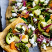 hummus pizza with vegetables on top of the thin crust