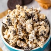 popcorn covered in melted chocolate and peanut butter in a teal bowl.