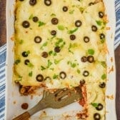 casserole with cheese and black olives and garnish on top in a white casserole pan